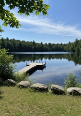 Fototapeta premium Serene Wooden Dock on a Calm Lake Surrounded by Lush Green Forest Under a Clear Blue Sky