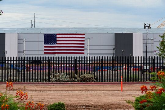 Exterior view of a data center building displaying an American flag, illustrating AI infrastructure, cloud computing, digital operations, and hyperscale facility development
