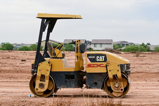 Caterpillar twin-drum road roller at a construction site, illustrating soil and asphalt compaction, road building, heavy equipment, and infrastructure development