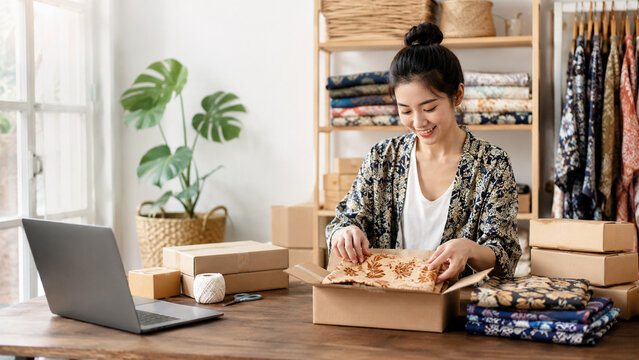 Southeast Asian woman entrepreneur packing handmade textile products at home