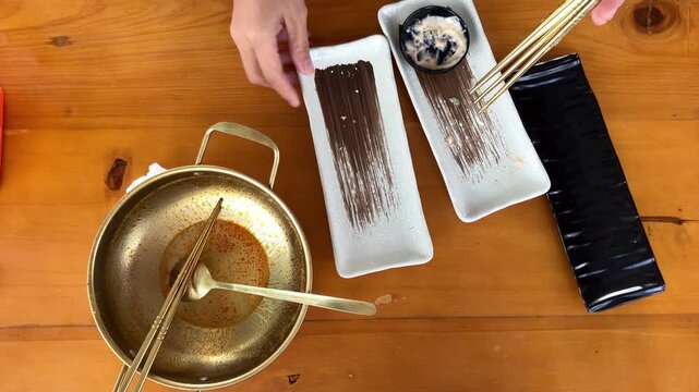 Close up of a woman's hands gathering and arranging dirty plates and cutlery after finishing a meal