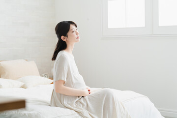 ベッドでくつろいでいる妊婦　ライフスタイルイメージ © aijiro