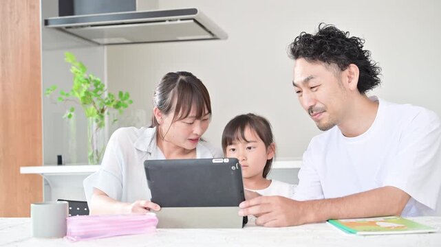 自宅のダイニングやリビングでタブレットを使って家庭学習をする親子3人の家族とデジタル教育のイメージの動画