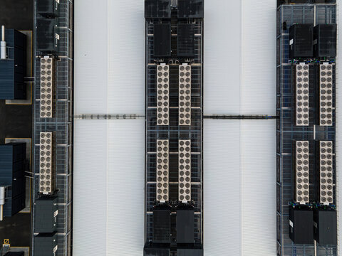 Aerial view of a data center facility featuring rows of cooling units and industrial equipment on a large white roof in Keflavik, Reykjanesbaer, Iceland.