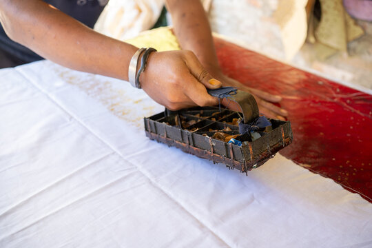 Artisan Applying Batik Stamp on White Fabric in Indonesia