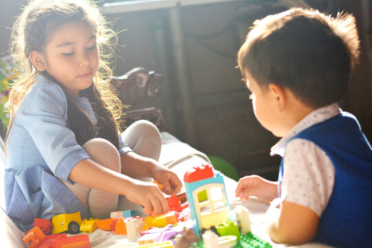 Adorable little siblings playing with building blocks.