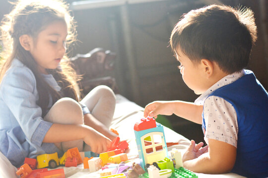 Adorable little siblings playing with building blocks.
