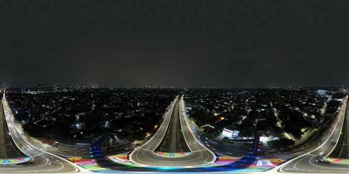 Aerial view of the illuminated Flyover Tapal Kuda Jakarta at night with colorful road markings and light trails from traffic in Pasar Minggu, Daerah Khusus Ibukota, Indonesia.