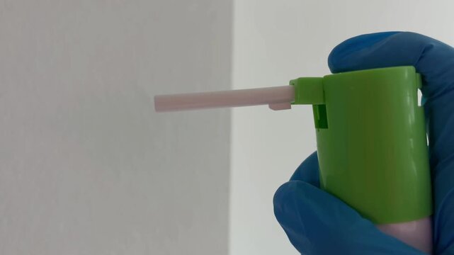 Close up of medical personnel using a throat spray with a long nozzle for oral care, pressing the pump to administer medication and relieve pain on a white background