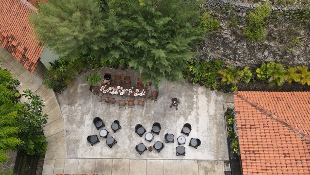 Aerial view of a courtyard with outdoor dining tables, chairs, and lush trees in Tanjungsari, Special Region of Yogyakarta, Indonesia.