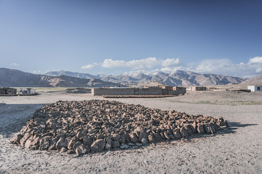 In a high-altitude village in the Pamirs, dung is dried for heating during the cold season; livestock feces lie on the ground in the village against the backdrop of the Tien Shan mountain peaks