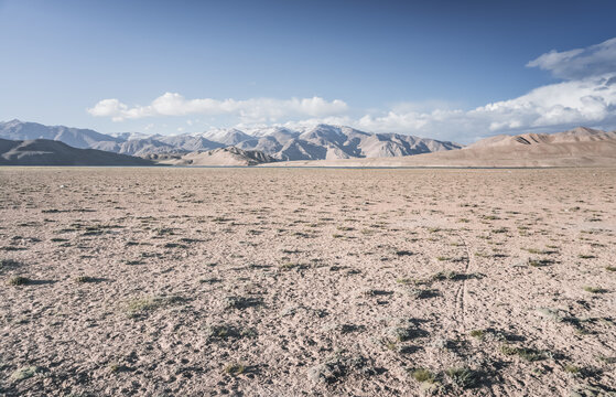 A desert landscape in the highlands of the Pamirs on a sunny summer day with mountains, peaks, and ridges of the Tien Shan mountain range