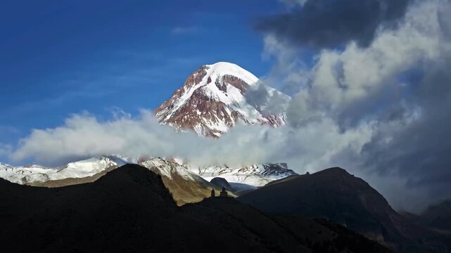 Snowy mountain peak emerging from moving clouds