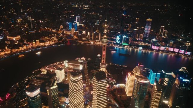 Wide aerial night panorama over Lujiazui peninsula, Pudong, Shanghai. The Oriental Pearl Tower, Jin Mao Tower and Shanghai World Financial Center rise above the financial district.