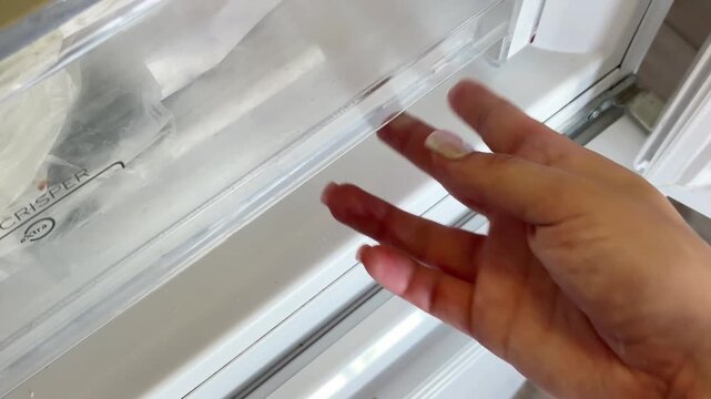 Woman's hand closing a refrigerator crisper drawer containing fresh, ripe yellow lemons for maintaining food freshness and following a healthy diet lifestyle