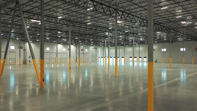 Slow aerial dolly shot inside a sprawling empty warehouse in Lancaster, California. 4K