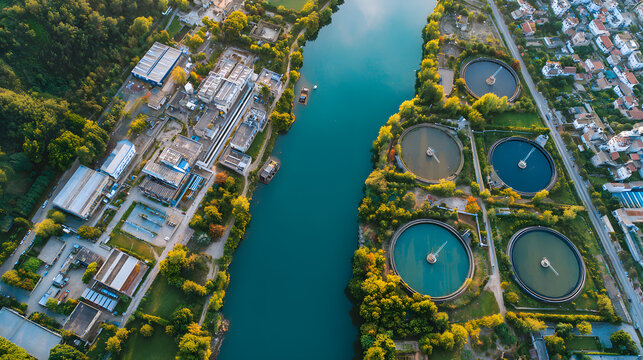 Aerial view of an industrial water treatment facility with multiple circular settling tanks near a river.