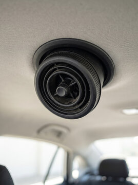 Round adjustable air conditioning vent on the ceiling headliner of a car cabin
