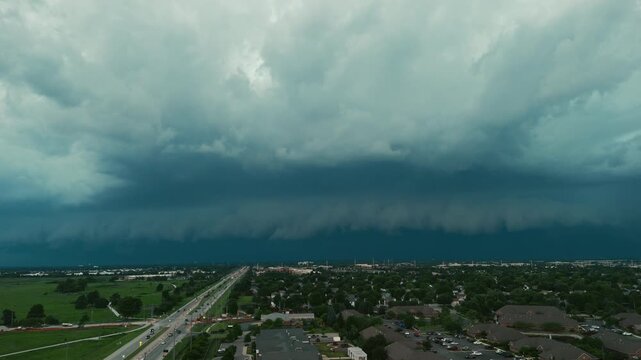Dark storm clouds forming over the countryside before severe weather. Dramatic shelf cloud approaching across open fields with an ominous sky, Wide aerial view