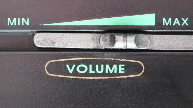Horizontal close up of finger moving silver volume slider from minimum to maximum and back