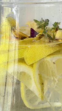 Woman's hand preparing a refreshing detox lemon water infused with mint and herbs, closing a glass pitcher with a lid for a healthy lifestyle and proper hydration
