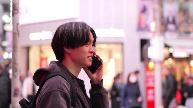 渋谷センター街でスマートフォンで話をする若い男性