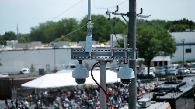 Police surveillance camera system mounted on a utility pole for public safety monitoring during a large outdoor event.
