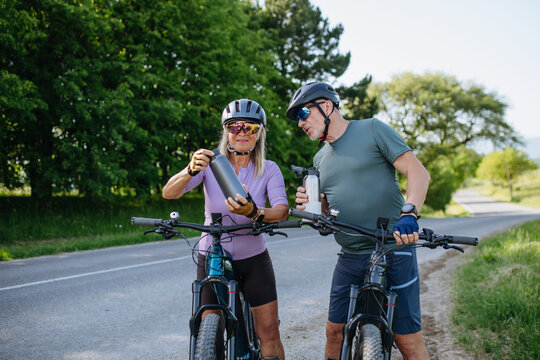 Mature couple resting and drinking water on electric bike tour.
