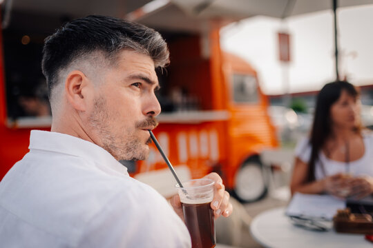 Man drinking iced coffee at outdoor food truck cafe