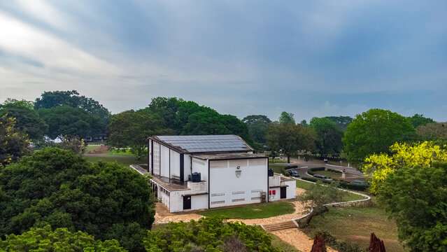 Aerial view of Achimota School building with solar panels on the roof, surrounded by lush green trees and a paved path in Achimota, Greater Accra Region, Ghana.