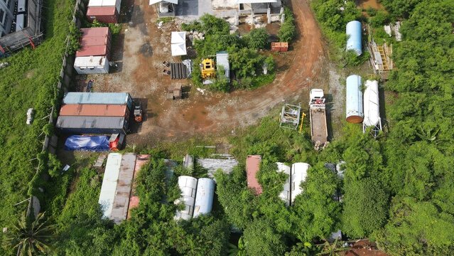 Aerial view of Bambu Apus site featuring shipping containers, large cylindrical tanks, and a truck parked amidst lush vegetation in Kecamatan Cipayung, Daerah Khusus Ibukota, Indonesia.