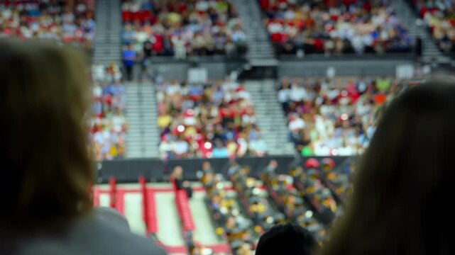 Blurred crowd of spectators sitting in stadium stands during large public event with shallow depth of field and abstract background