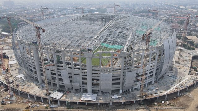 Aerial view of Jakarta International Stadium under construction with cranes and structural steel framework in Tanjung Priok, Jakarta, Indonesia.
