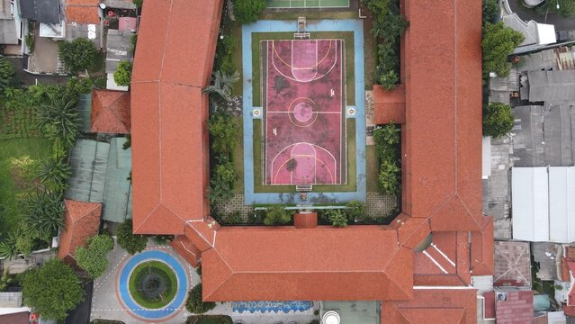 Aerial view of Pondok Labu school courtyard featuring a basketball court surrounded by red tile roofs in Cilandak, Jakarta, Indonesia.