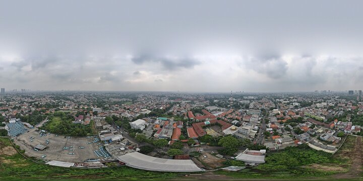 Aerial view of Pondok Labu featuring dense residential rooftops, lush green trees, and urban infrastructure under a cloudy sky in Cilandak, Jakarta, Indonesia.