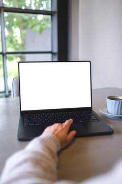Vertical mockup image of a woman working and typing on laptop computer with blank white desktop screen in cafe