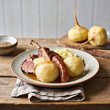 Traditional Norwegian Raspeballer, large handmade potato dumplings served with smoked lamb, sausage, melted butter and mashed rutabaga