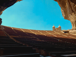 The grand rock-cut amphitheater of the Coptic Cave Cathedral with Christian church domes against a clear blue sky, Cairo © Kerolos
