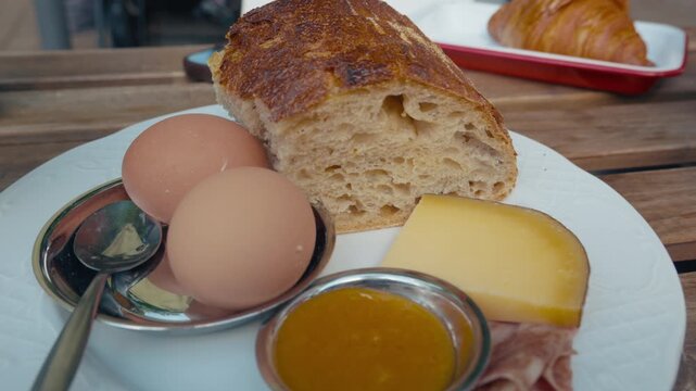 A continental breakfast of a soft boiled egg, fresh bread, cheese and orange juice on a table.