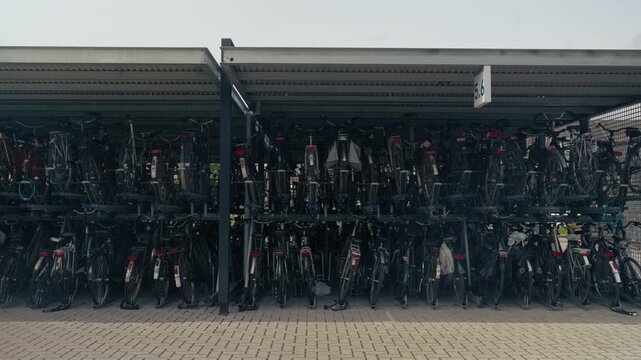 Rows of parked bicycles lined up on two-tier racks in a busy covered bicycle parking area.