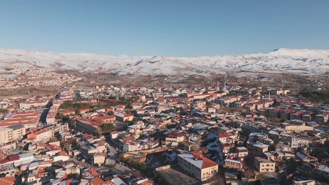 Establishing aerial flyover of Urgup with snowy mountains, backward flight, sunny day, 4K