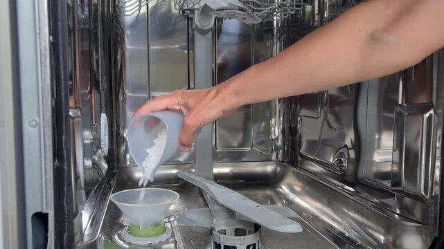 The process of refilling the salt compartment in a dishwasher at home. Care of kitchen appliances