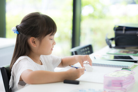 教室で集中して取り組む幼稚園・小学生位の女の子・塾や学校、受験や勉強、単語帳を見る学習のイメージの横顔