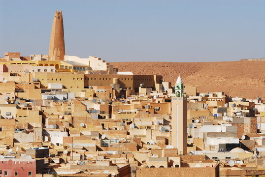 Algeria, Ghardaia, view of city with mud-brick dwelling and tall minaret against clear sky