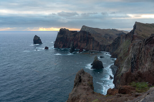 Aerial view of rugged volcanic cliffs and rocky sea stacks along the coastline of Madeira.