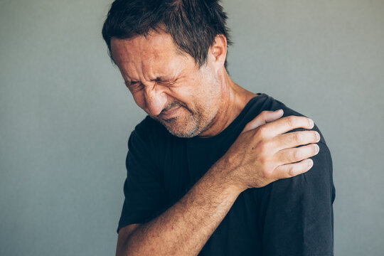 Man grasps his shoulder in visible pain