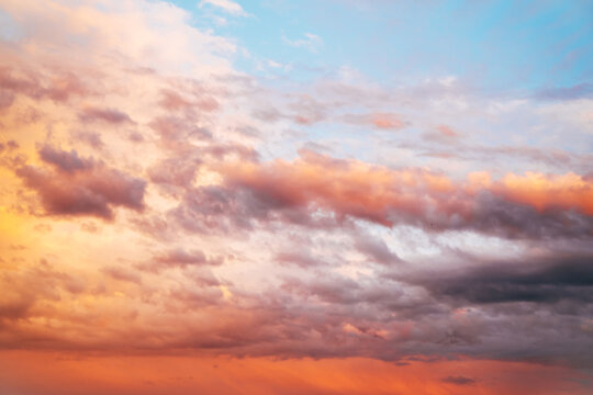 Dramatic sunset sky filled with colorful clouds illuminated by warm evening light. Atmospheric nature background with vibrant orange, pink and blue tones.