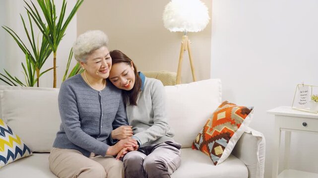 Overjoyed elderly grandmother mum, grownup daughter woman hugging, leaning on each other, chatting having fun pleasant conversation on cozy couch, family connection sharing secrets on weekend