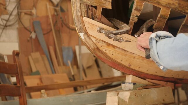 Shipwright clamping hull plank repair on wooden boat bow