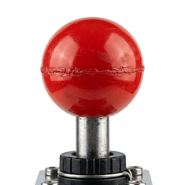 Close-up of a red spherical joystick button on a metallic control panel with isolated transparent background